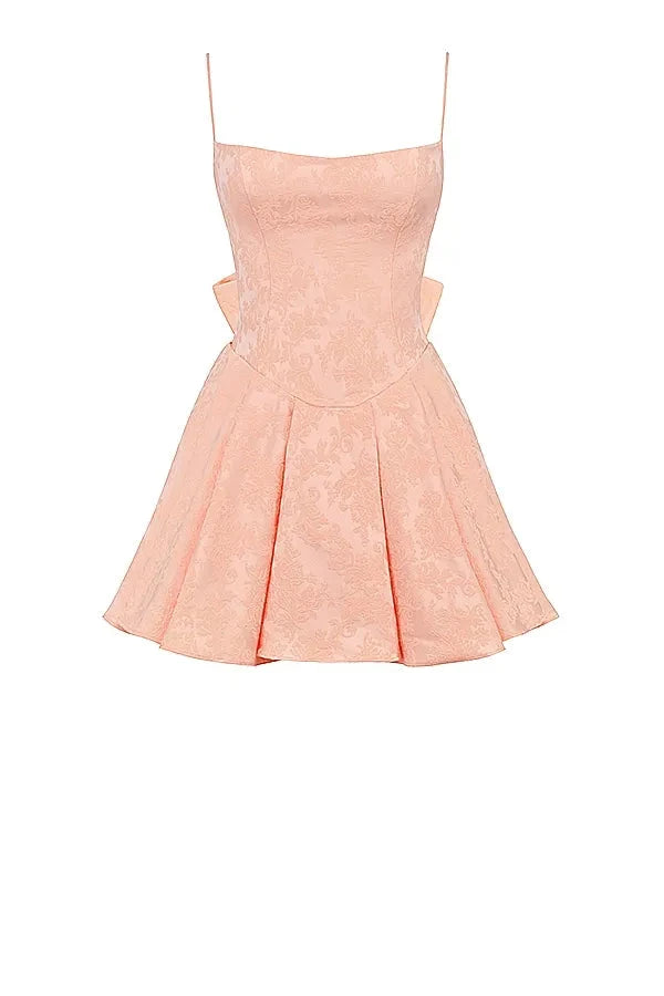 Model wearing Kouvr Ayliah peach jacquard mini dress with large bow detail at the back