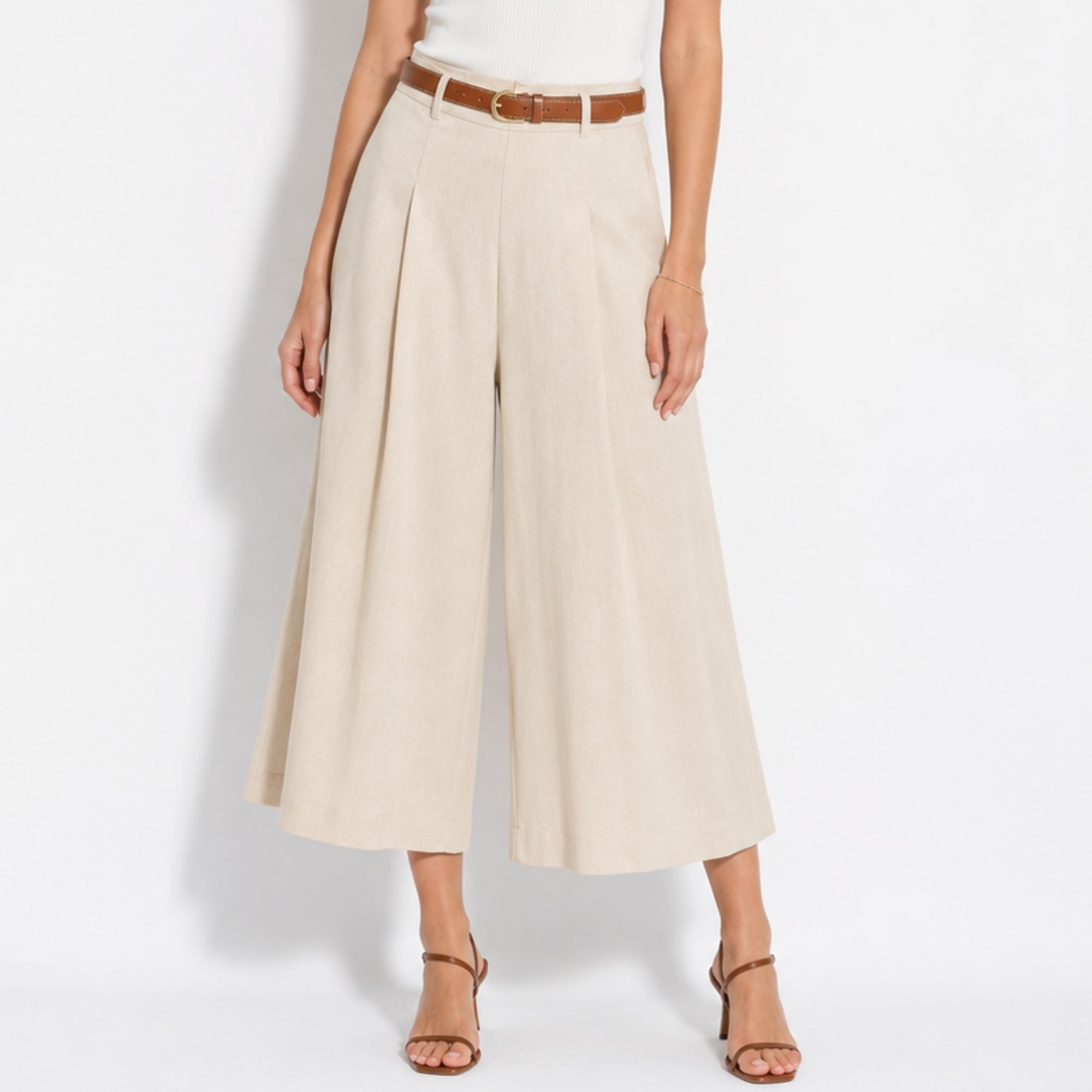 Woman wearing high waisted beige linen wide leg cropped trousers with brown belt.
