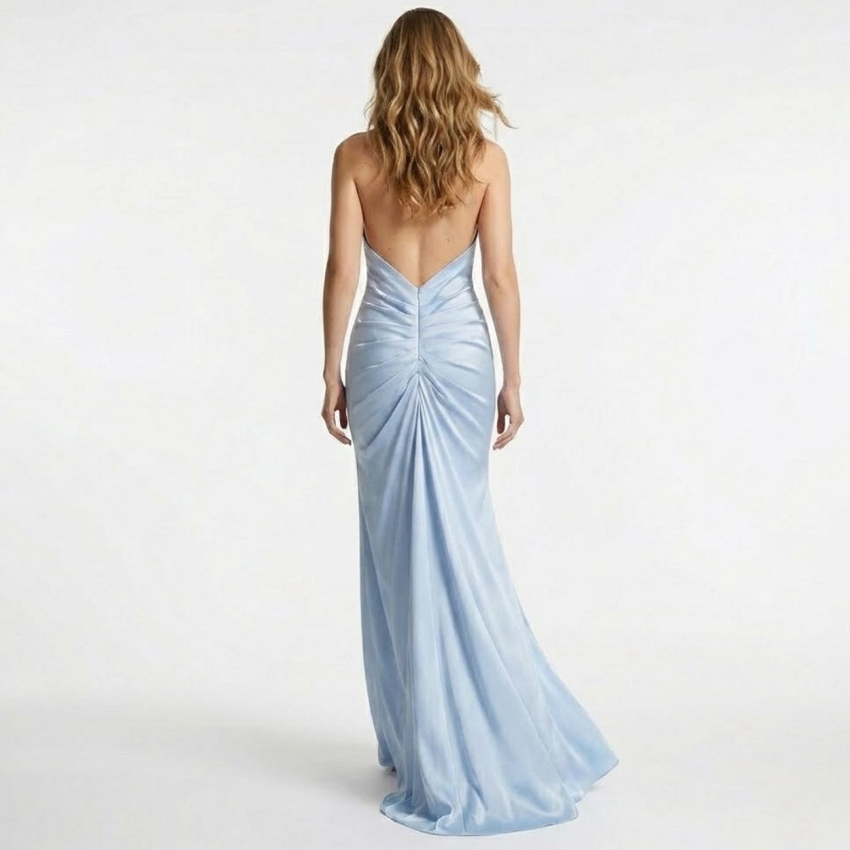 Back view of a model in the light blue Beverly satin gown, highlighting the completely open back and ruched detail at the waist.