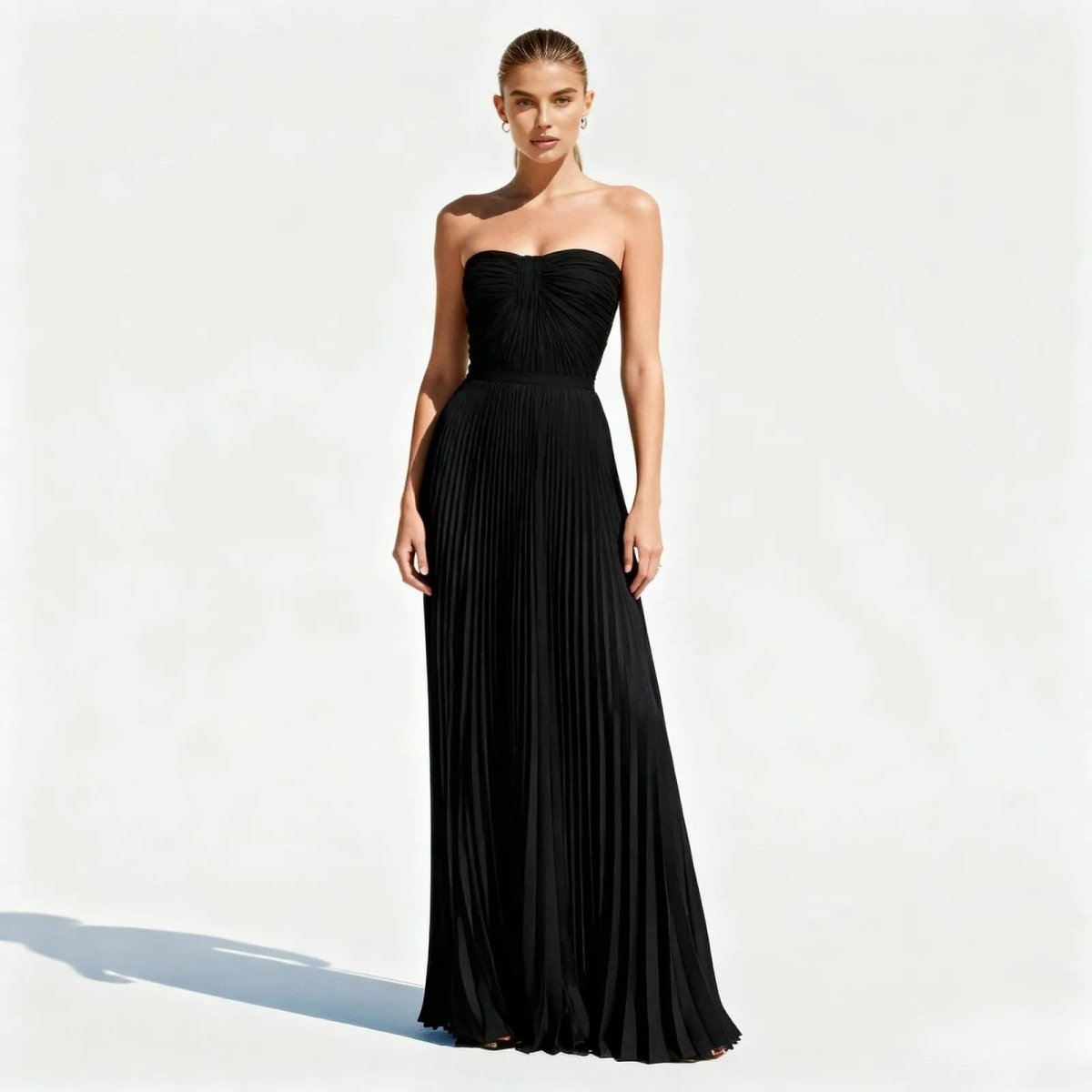 Woman wearing a black kouvr strapless gown on a white background