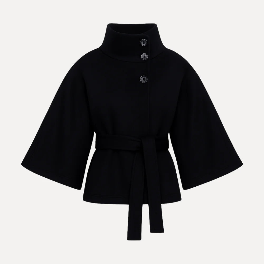 Model wearing the Kouvr black wool funnel neck cape coat with a tie waist belt, styled with light wash denim