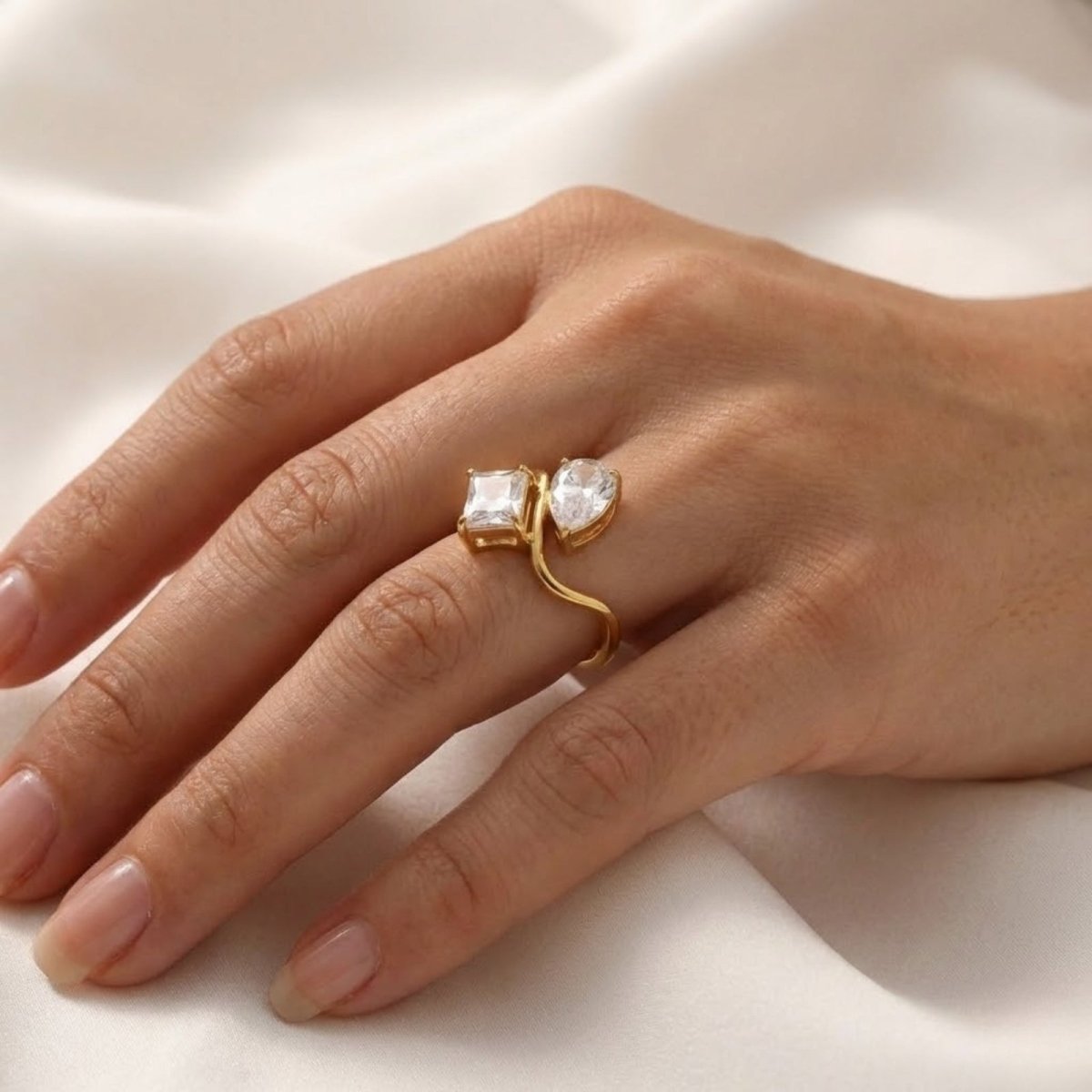 Close up of a woman's hand wearing the Kouvr Blanca gold Toi et Moi ring, showcasing the open bypass design.
