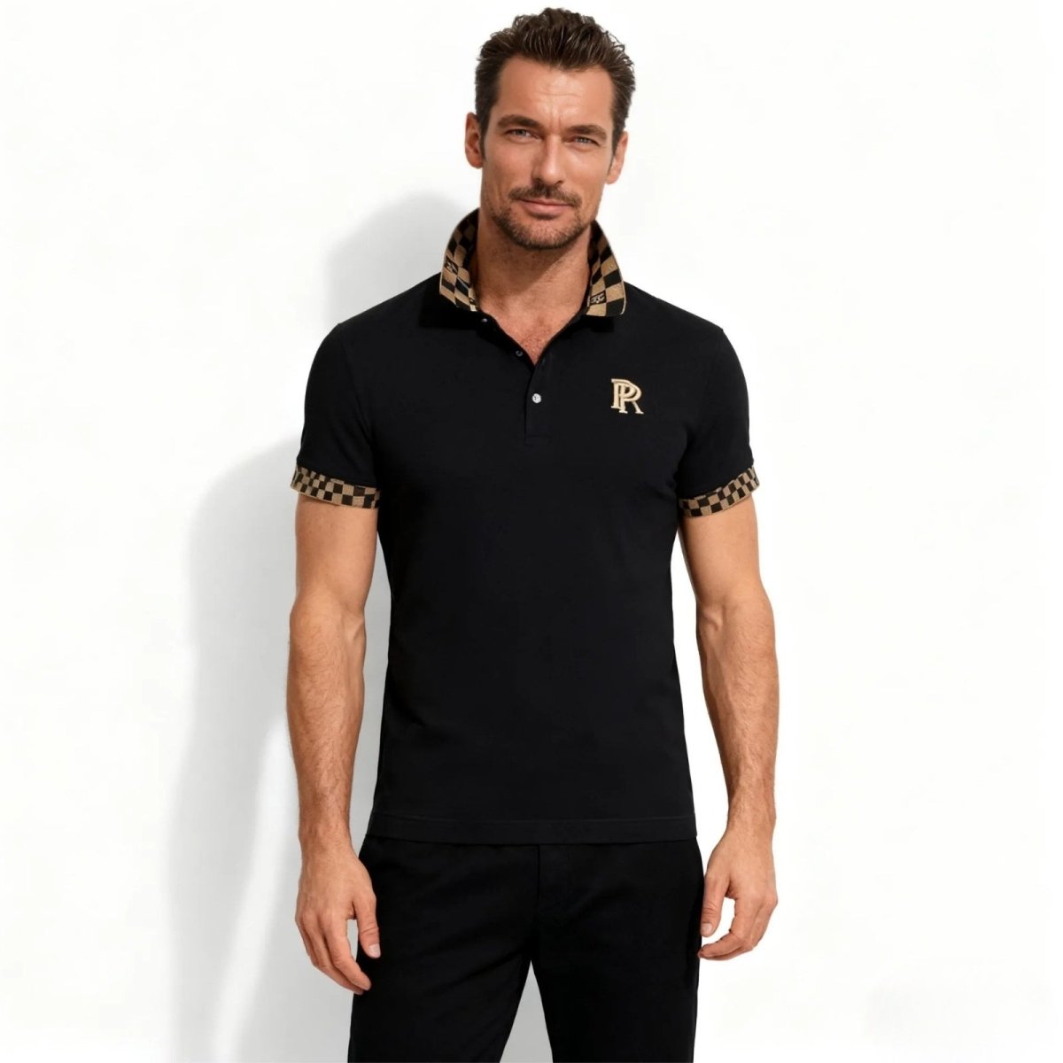 Model wearing the Kouvr men's slim fit black polo shirt with a brown and beige checkerboard collar and sleeve cuffs, featuring a gold R crest on the chest. 