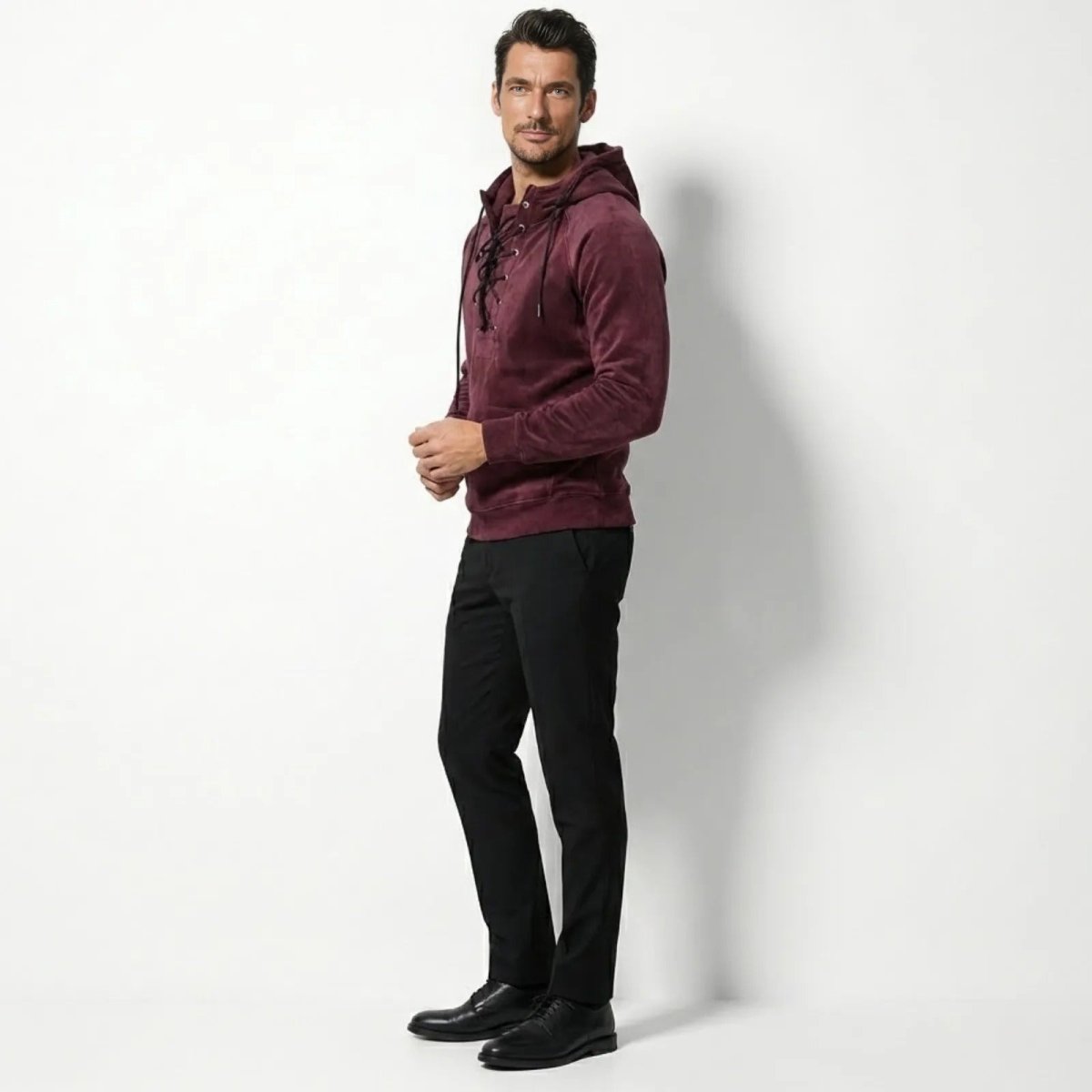 Side profile of a male model in a Kouvr burgundy lace-up hoodie, highlighting the tailored fit and raglan sleeve detail.