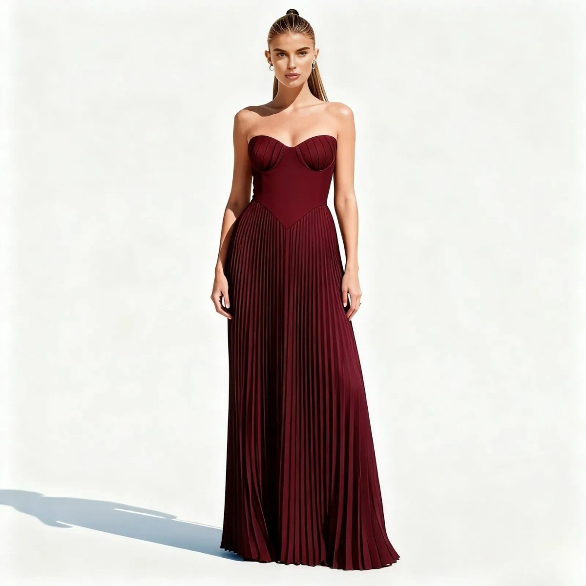 Woman wearing a burgundy kouvr strapless gown on a white background