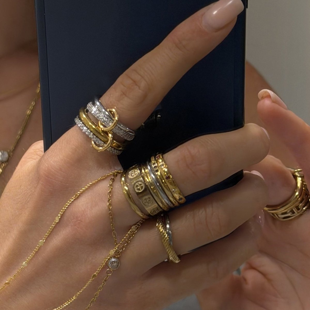 kouvr and wearing multiple gold and silver rings on a blurred background
