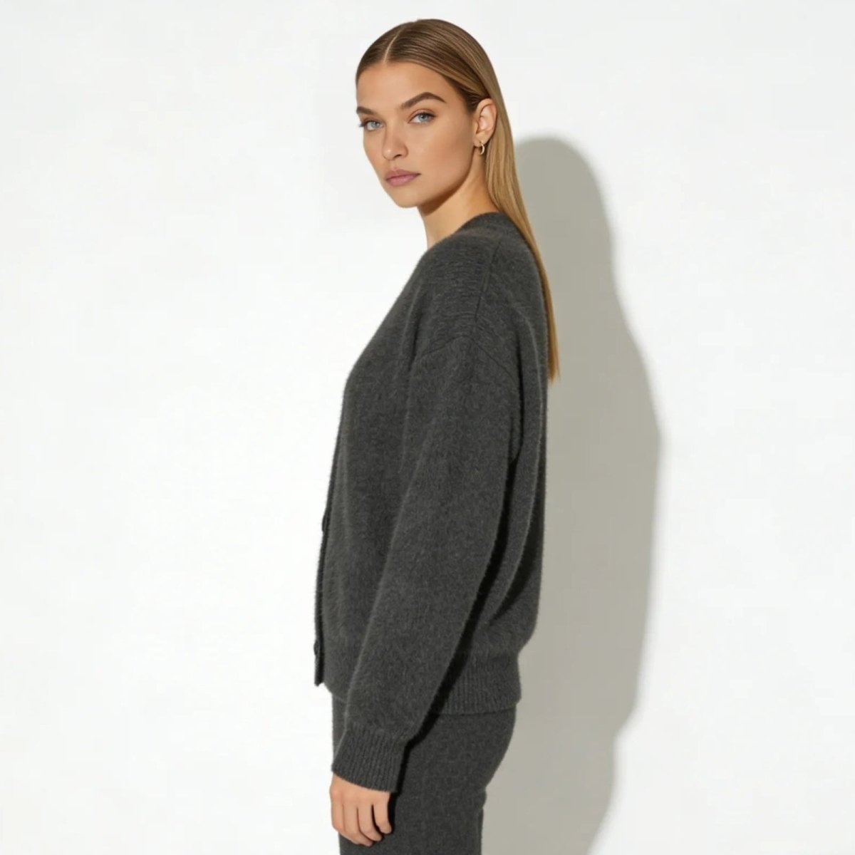 Side profile of a model wearing the relaxed-fit Kouvr Fashion dark gray cashmere cardigan to show its silhouette.