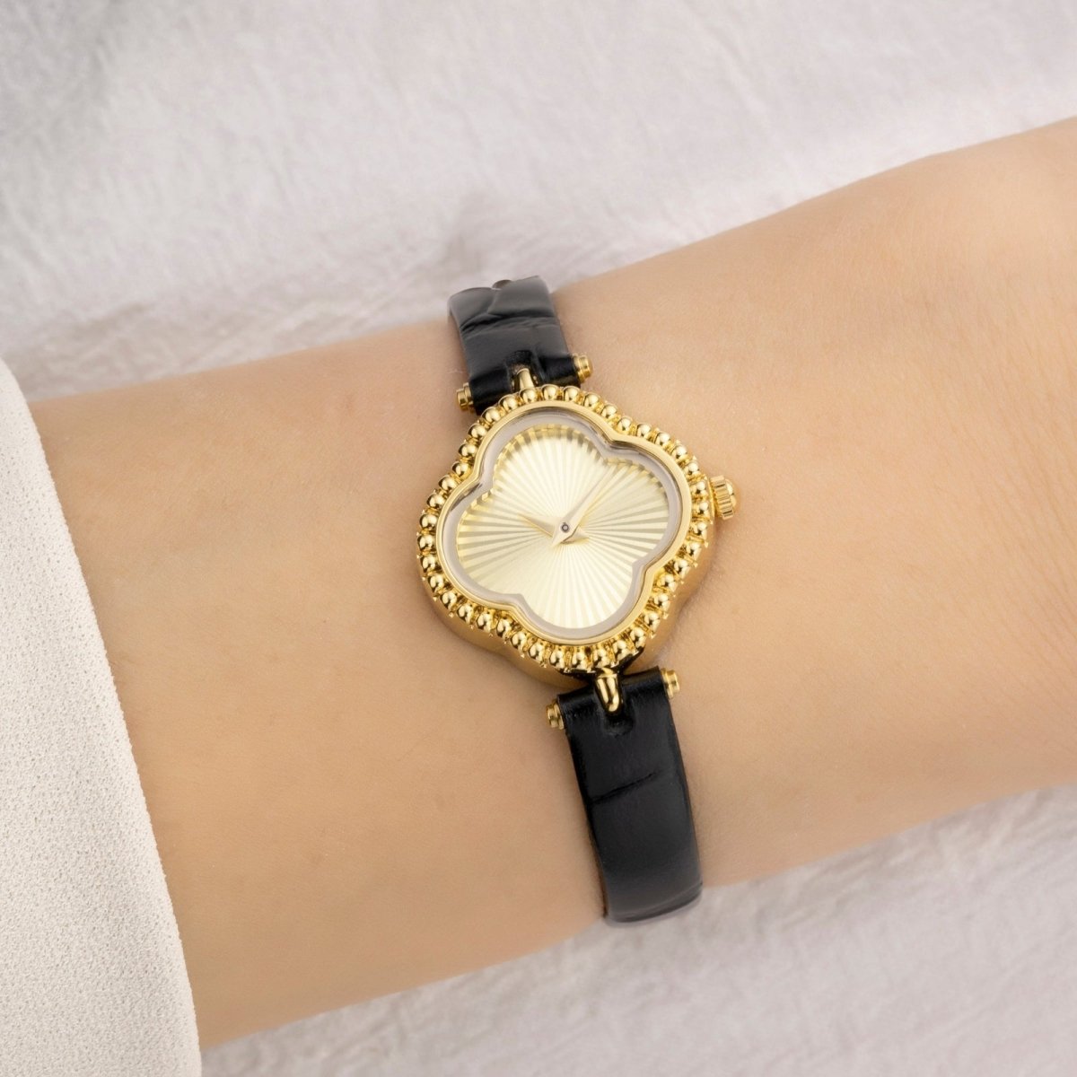 Wrist wearing a gold and black Kouvr watch on a white background