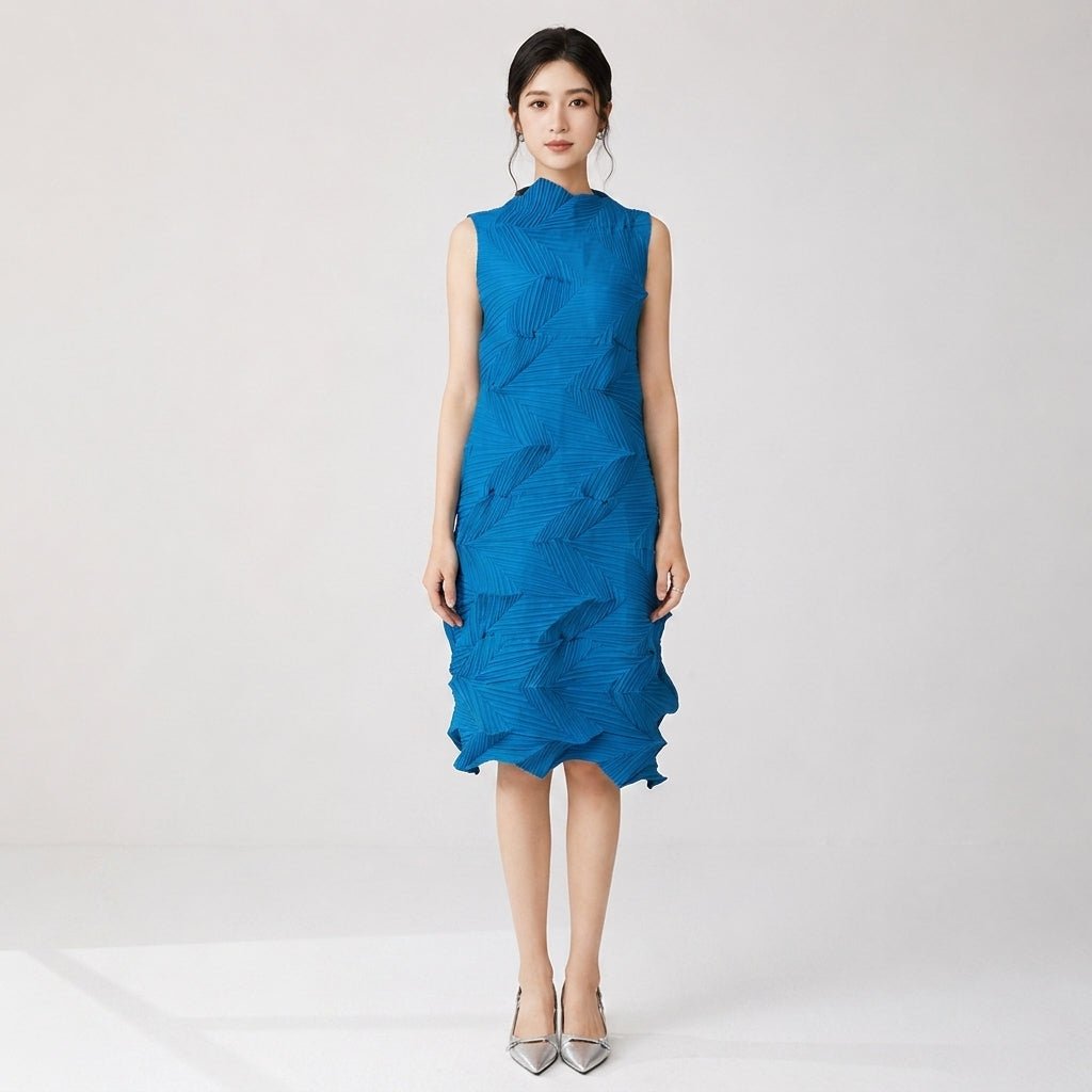 Front view of Asian female model wearing Kouvr cobalt blue architectural pleated sleeveless midi dress with silver heels in a studio setting.