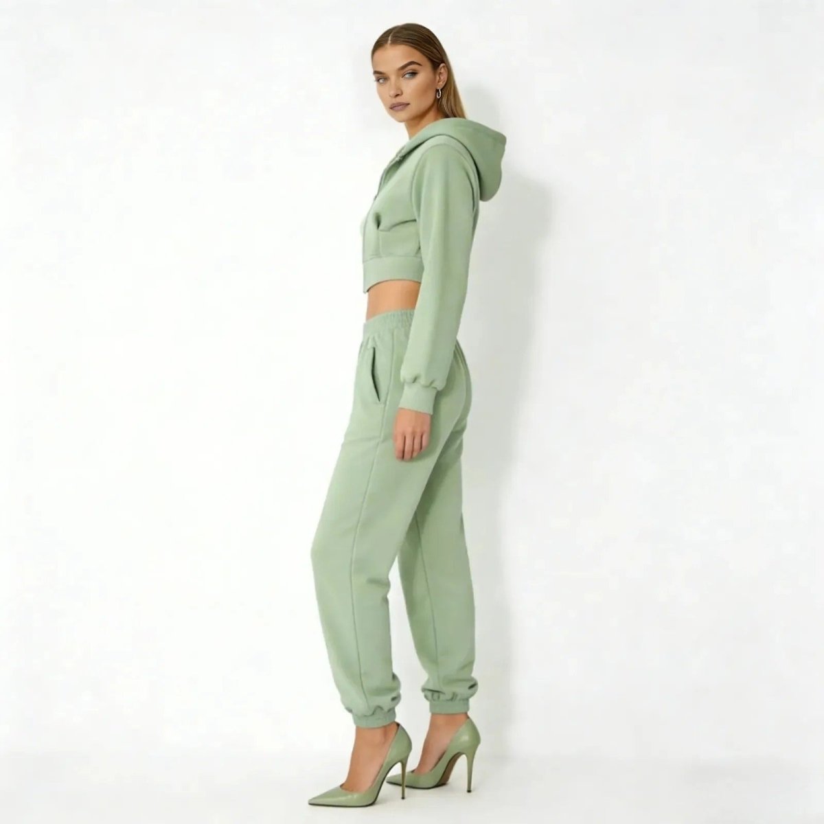 Side profile of a model in the Kouvr green loungewear set showing the cropped fit of the hoodie and silhouette of the joggers.