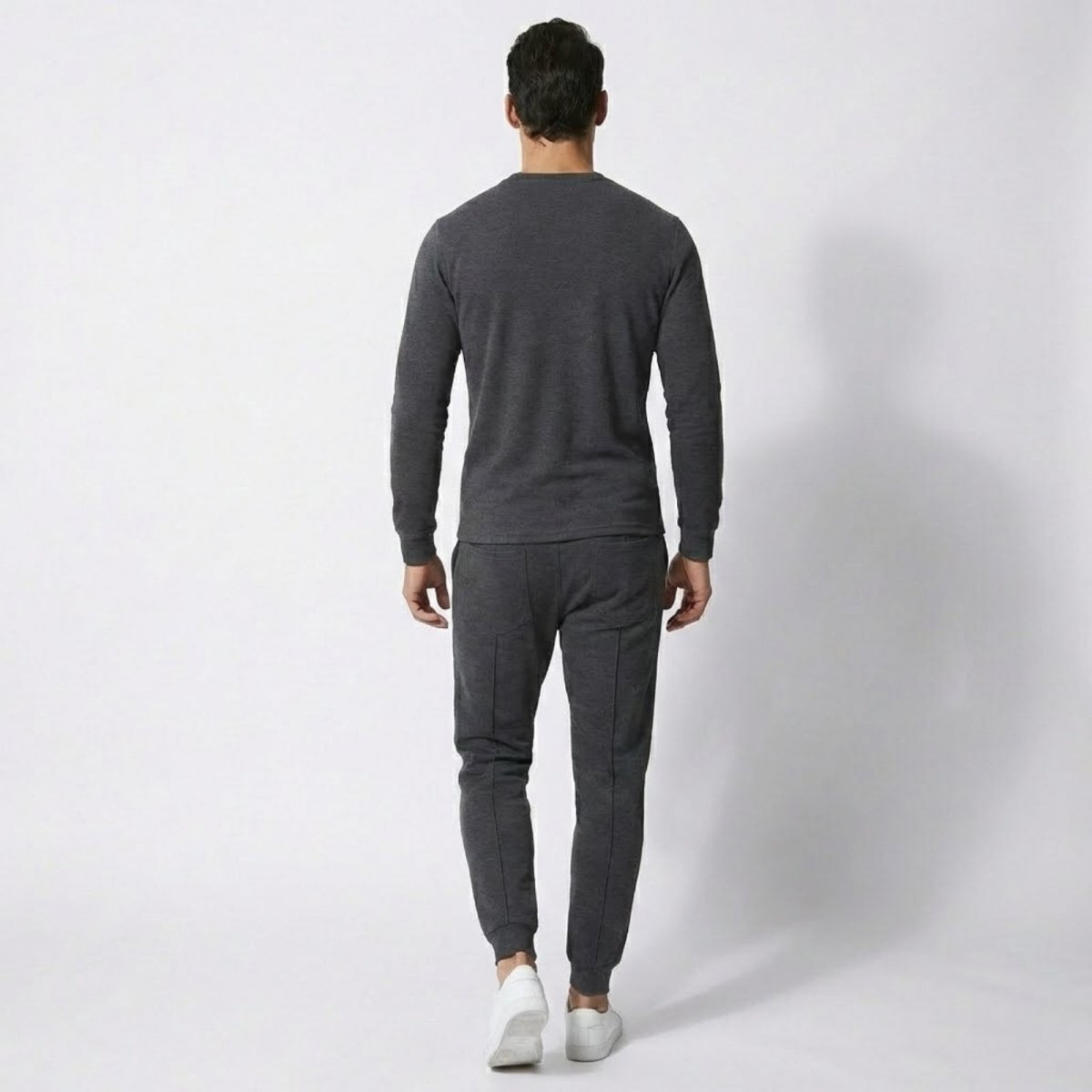 Back view of a man wearing the Kouvr Crue Knit Lounge Set in dark grey to show the garment's drape and fit.