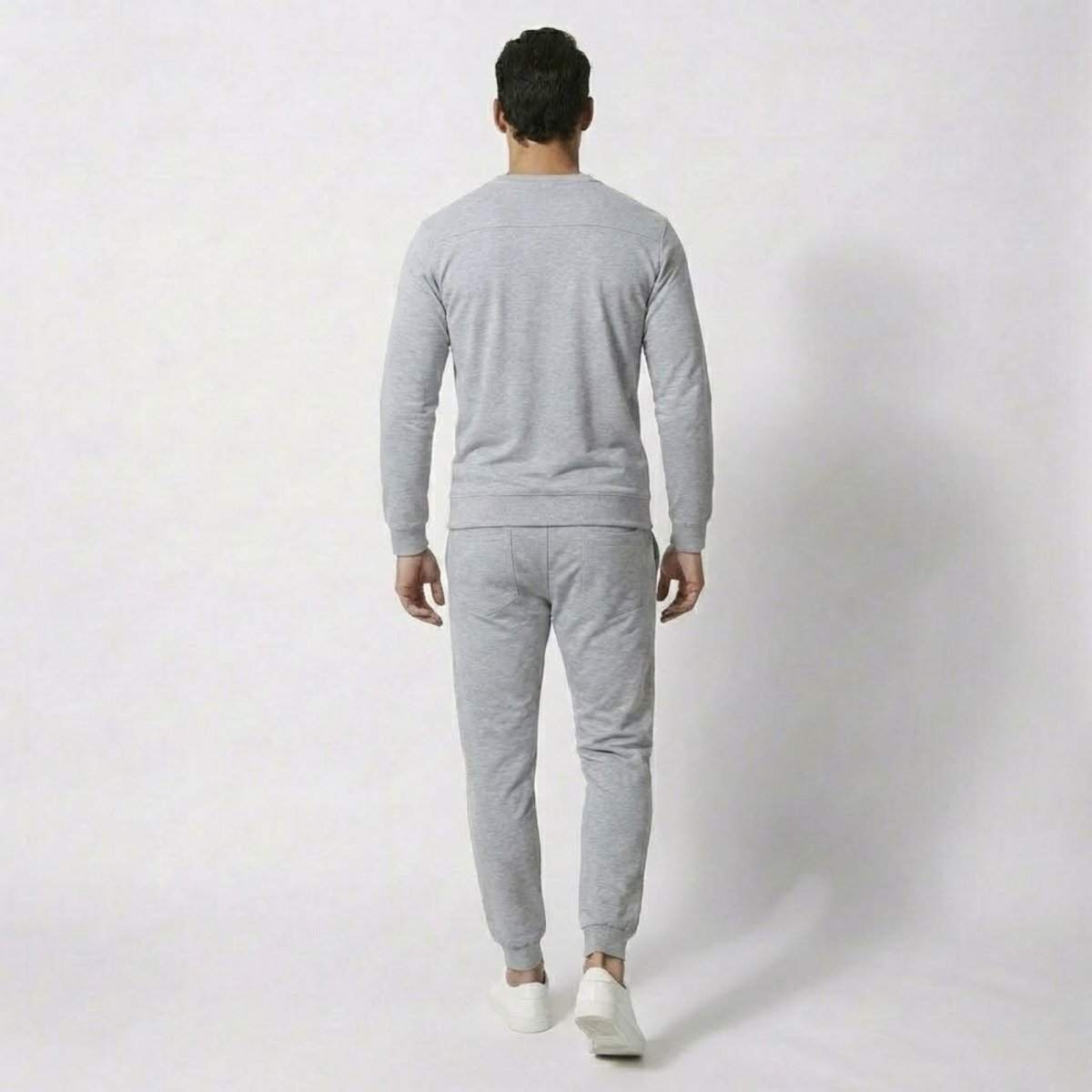 Back view of a man in the Kouvr Crue heather light grey sweatsuit, highlighting the structured yoke detail on the sweatshirt and the tailored fit.