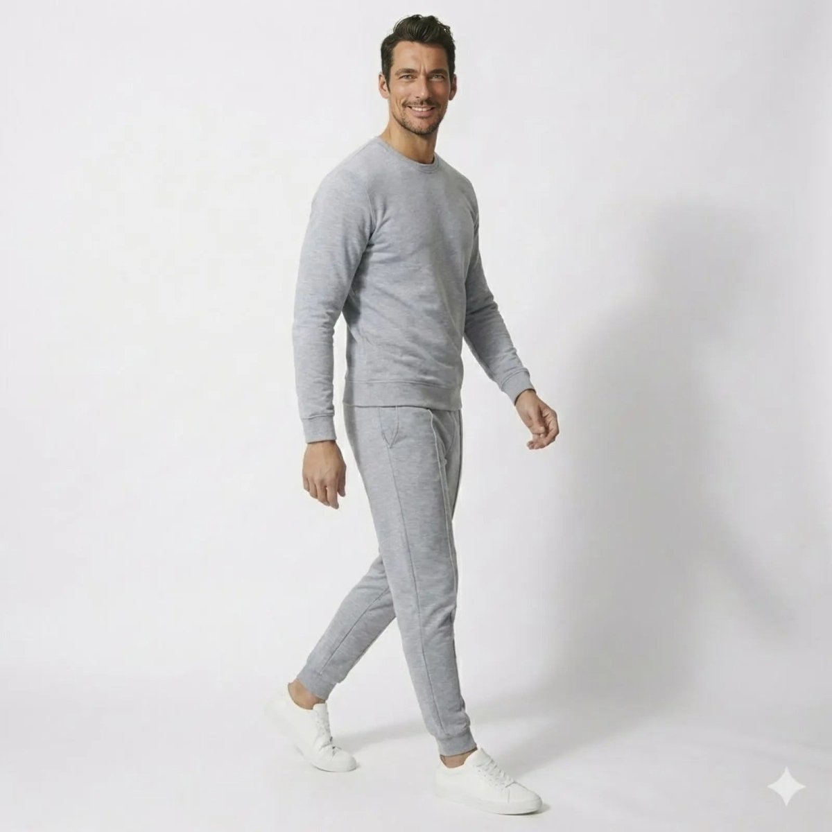 Side profile of a man walking in the Kouvr Crue Set heather light grey premium cotton lounge set, showing the tapered fit of the joggers and minimalist design.