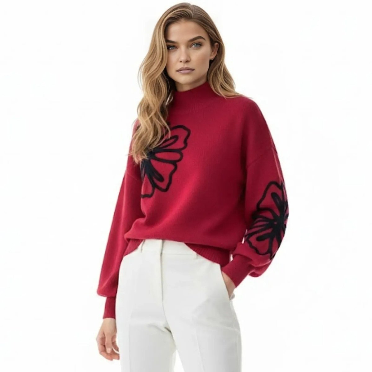 Model wearing the Kouvr Cynthia red mock neck sweater with black floral embroidery, paired with white trousers, front view.