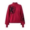Product-only image of the crimson red mock neck sweater from Kouvr Fashion, showcasing the large black flower embroidery on the chest and sleeve.
