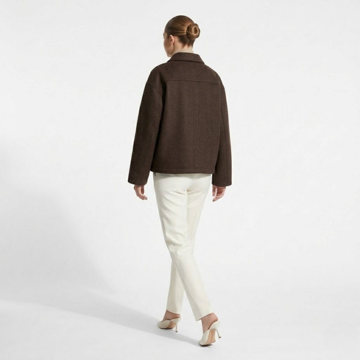 Back view of cropped dark brown winter jacket showing horizontal yoke detail and dropped shoulders.