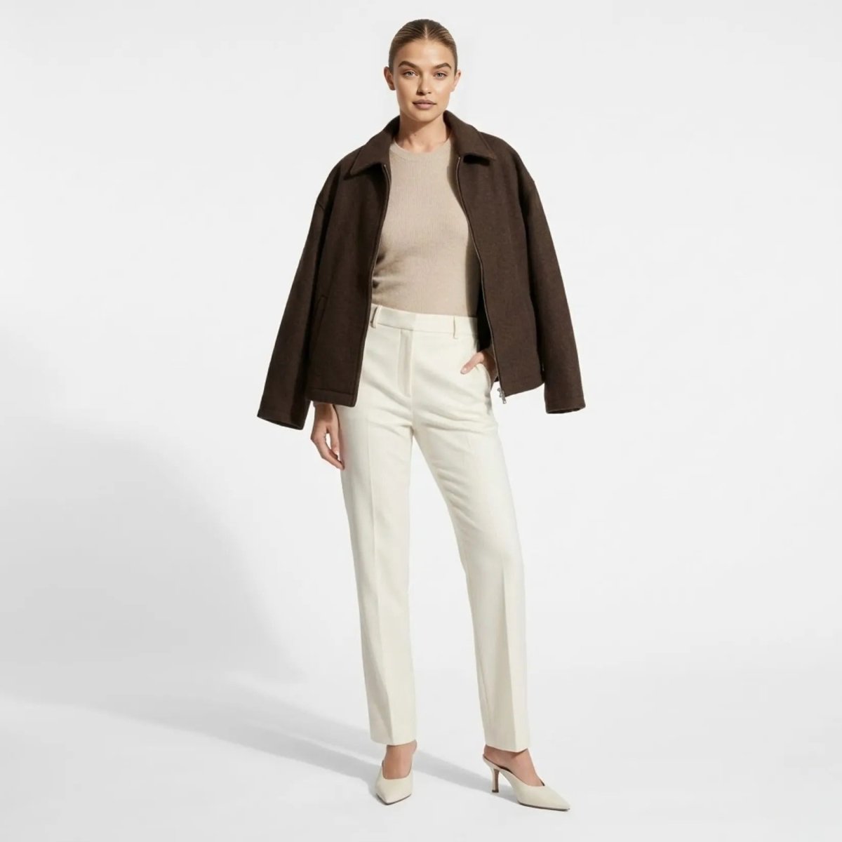 Woman wearing Kouvr dark brown wool blend zip-up collared jacket with cream trousers.
