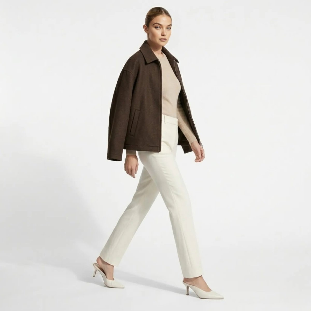 Side profile of woman walking in minimalist relaxed fit dark brown jacket by Kouvr.