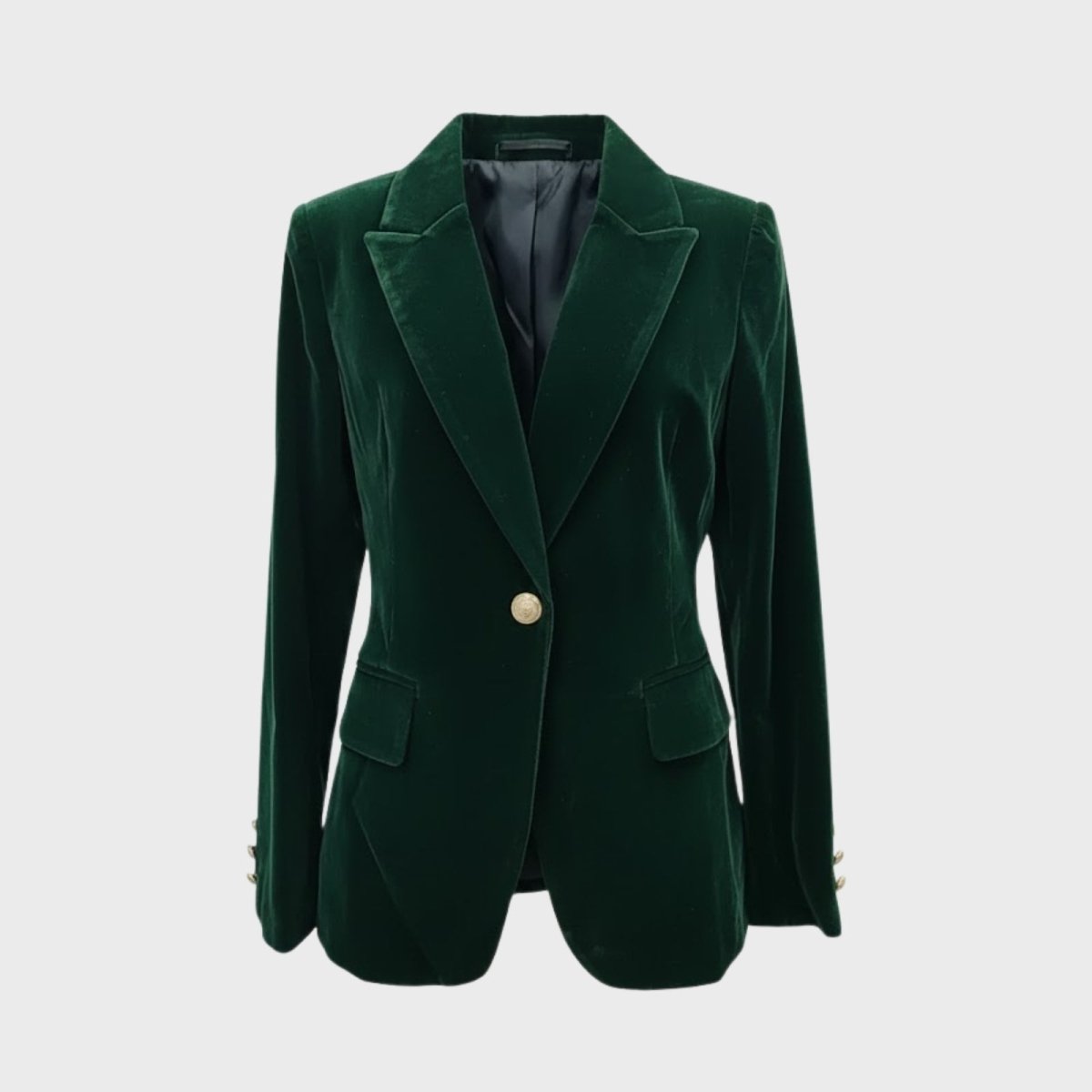 Product flat lay of the Kouvr dark green velvet blazer showing the single gold button closure, notched lapels, and rich velvet texture.