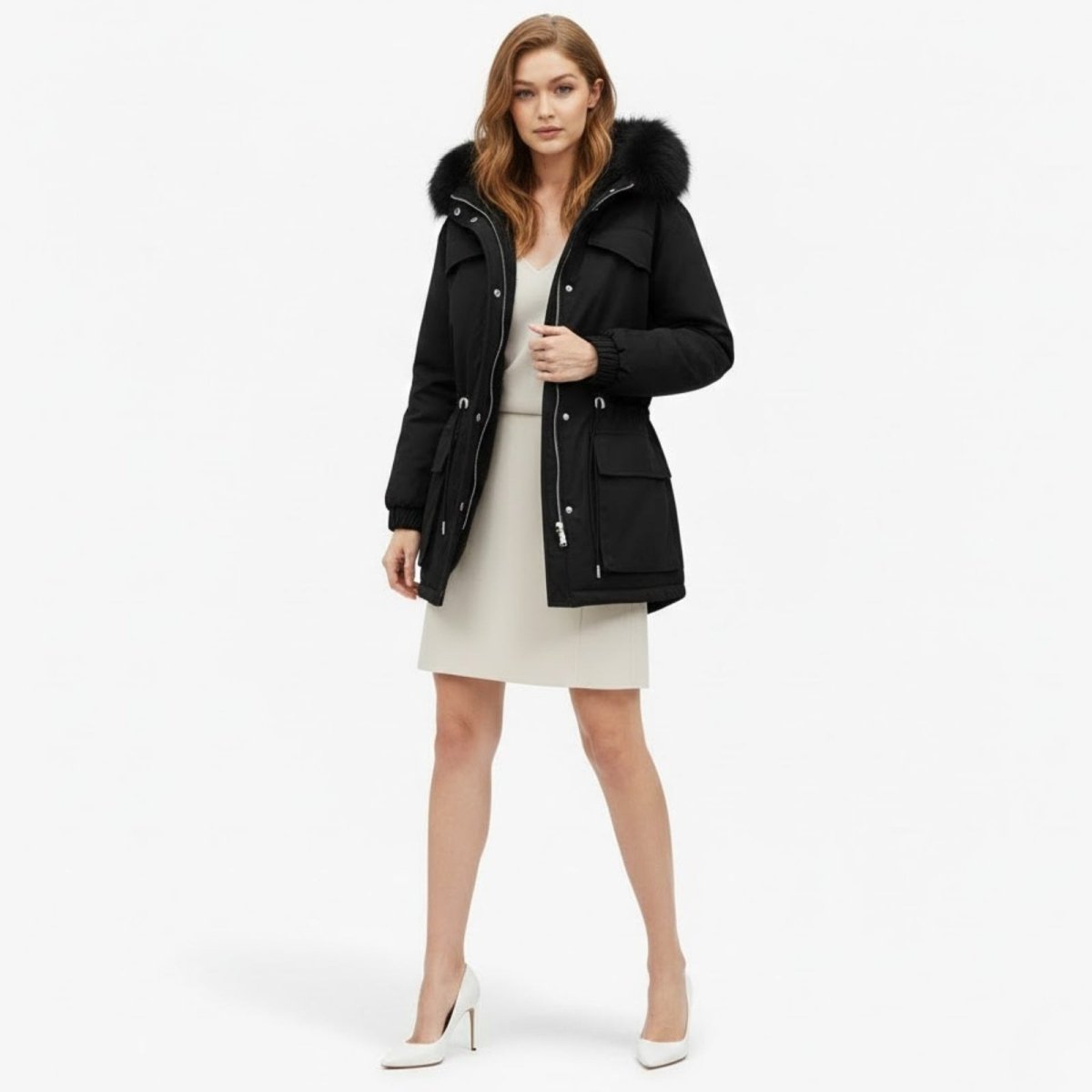 Model wearing the black Debra Parka from Kouvr Fashion, shown from the front with hands in pockets and a cinched waist, highlighting the faux fur hood.