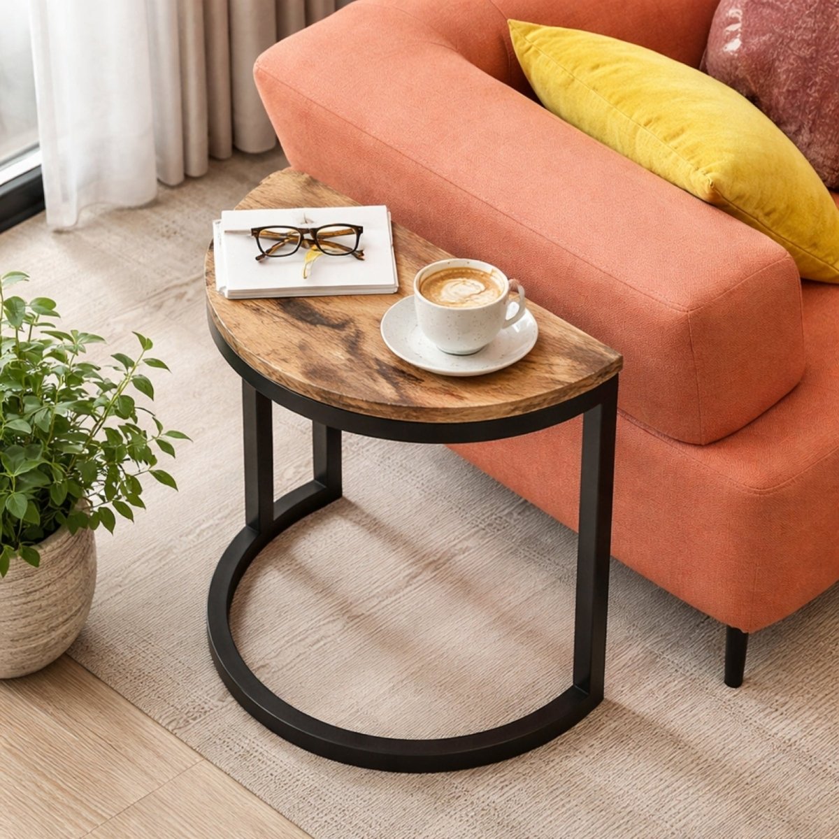 Top-down view of half moon accent table next to orange armchair, styled with coffee and plant, highlighting curved edge safety.