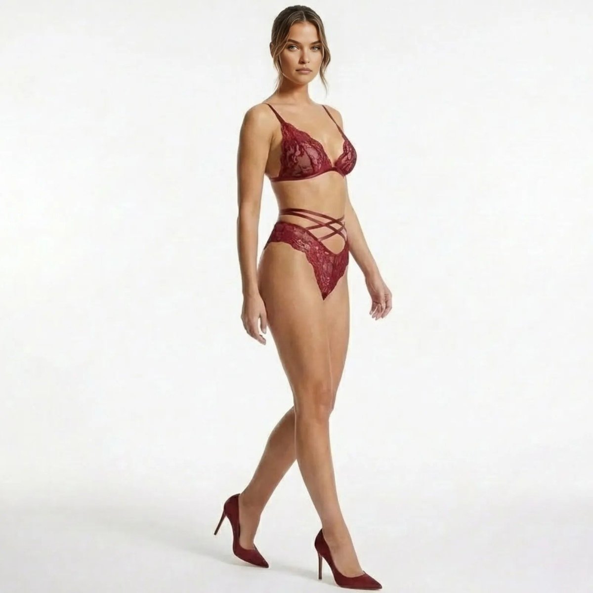 Model in a side profile walking in the Kouvr Desiree strappy wine red lace lingerie set and red heels.
