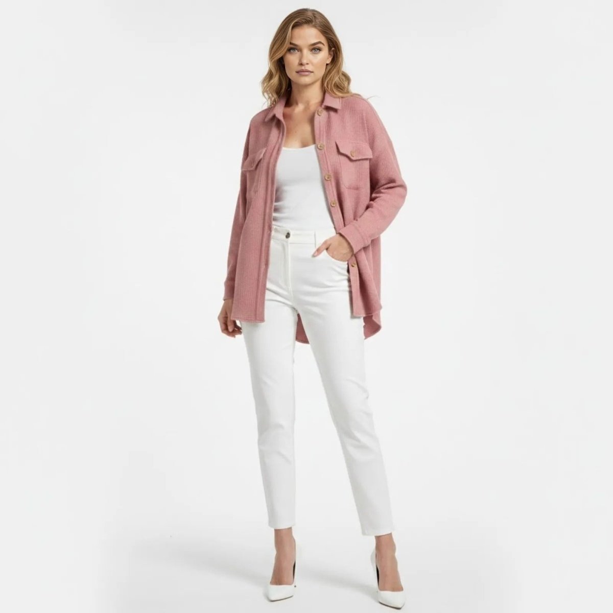 Model wearing the Kouvr Donna Oversized Waffle Knit Shacket in pink, styled open over a white tank top and white trousers.