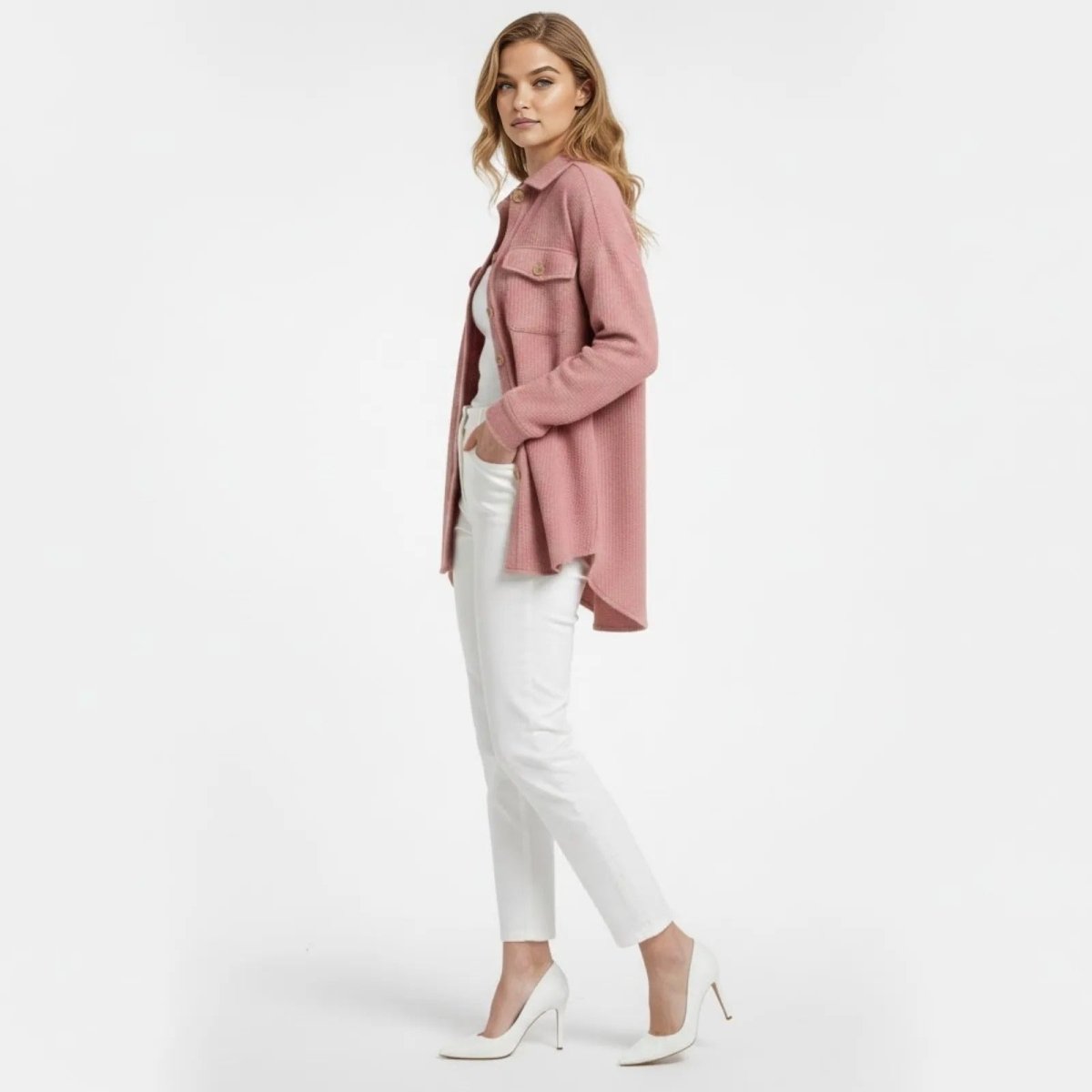 Side profile of a woman in a pink waffle shirt jacket showing its high-low hem and relaxed fit, by Kouvr fashion.