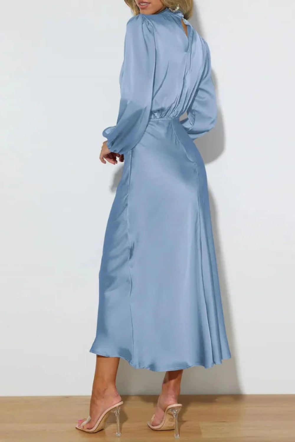 Model wearing the Kouvr Ellana blue satin long sleeve midi dress from the back