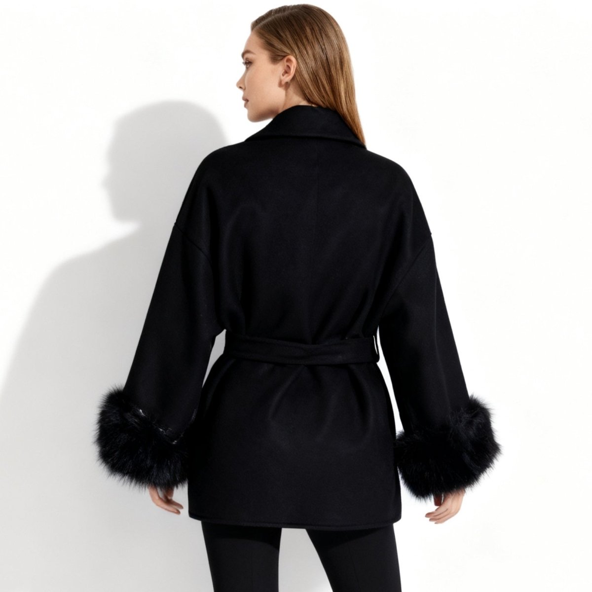 Back view of the Kouvr Emma black winter coat showing the drape of the wool and the removable tie belt.