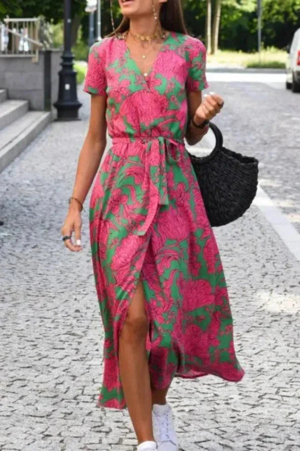 Model wearing Kouvr Fashion pink floral midi wrap dress walking on a cobblestone street