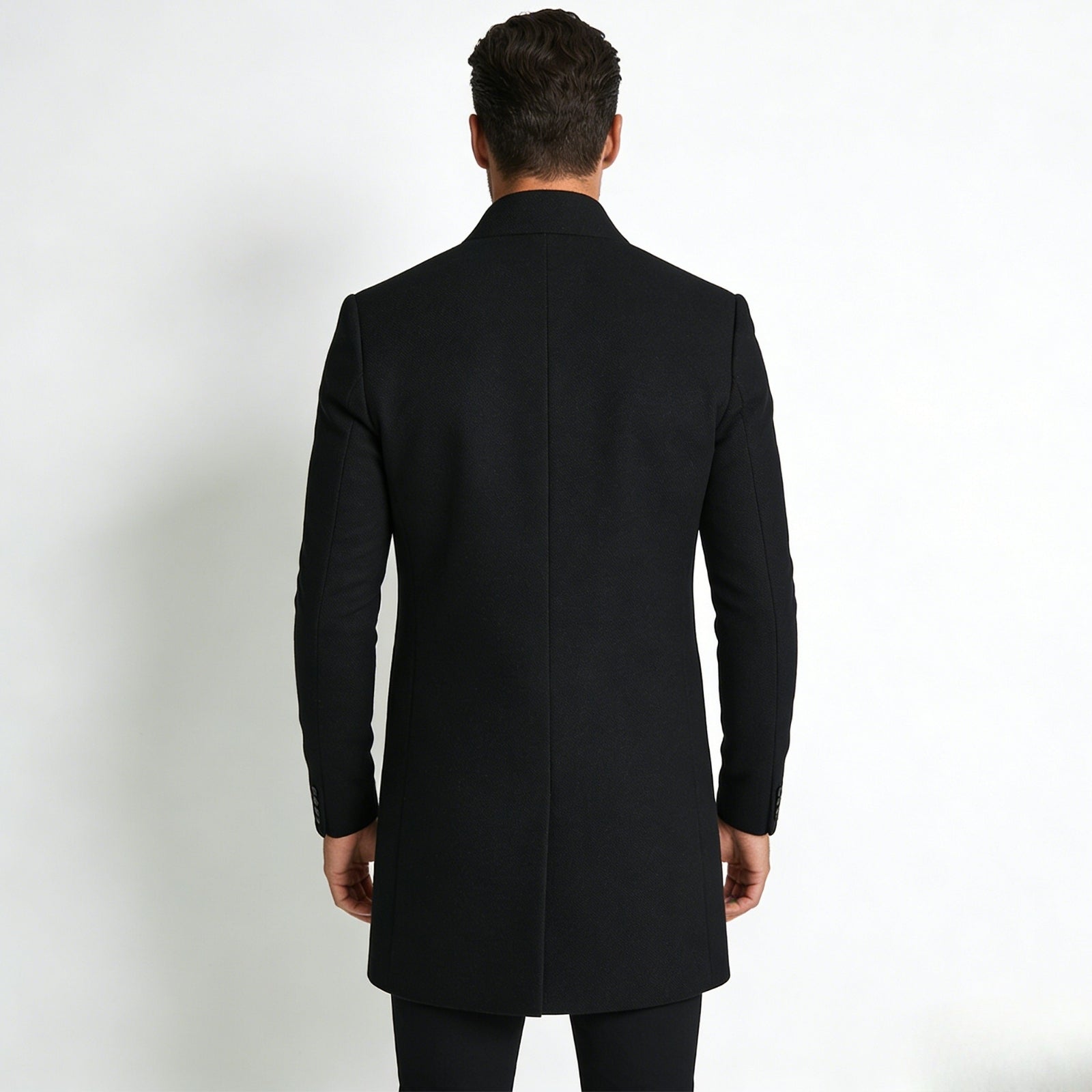 Back view of a male model wearing the Kouvr Fashion Archie black winter topcoat, highlighting the single back vent and structured shoulders.