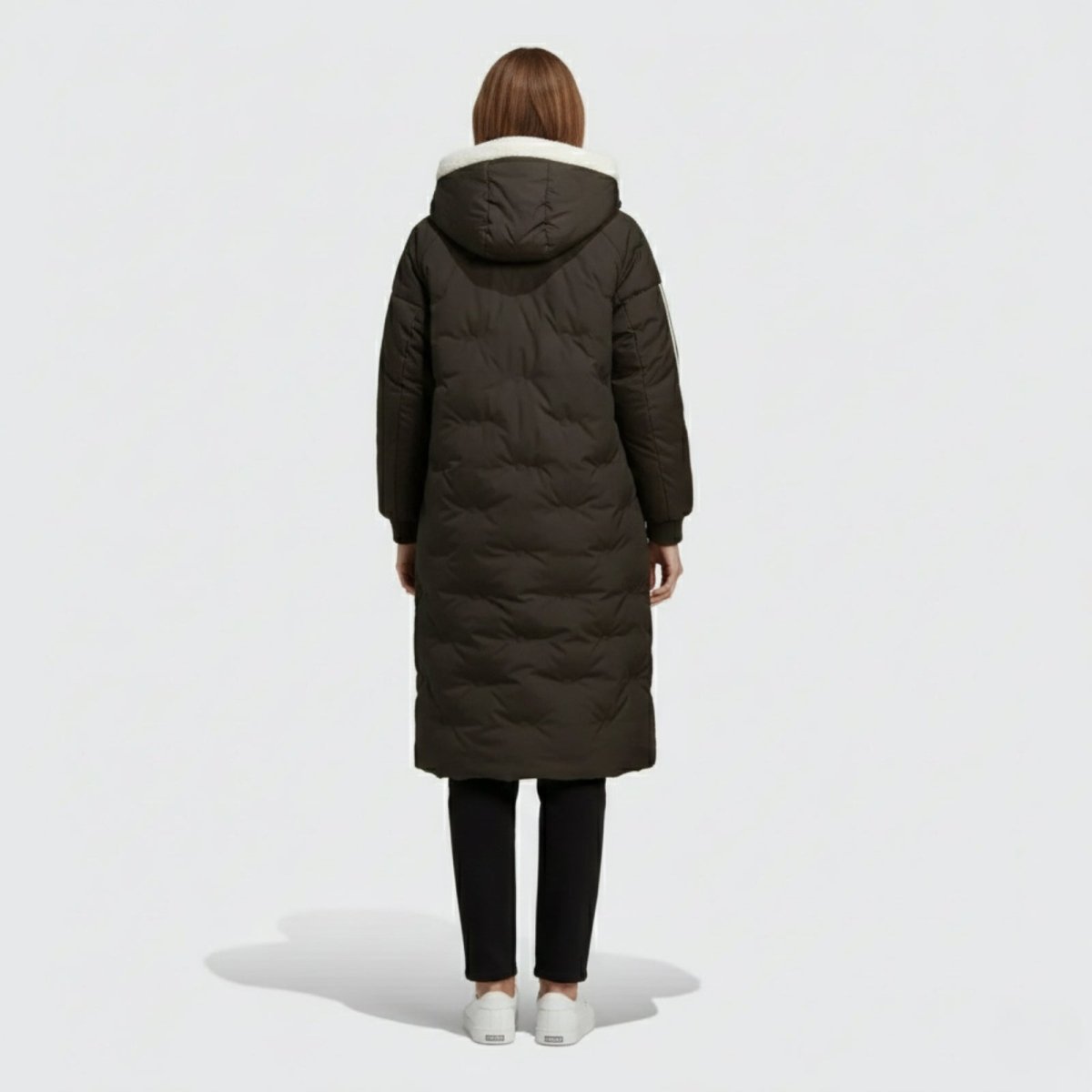 Back view of a model wearing the Kouvr Arianne hooded down parka, displaying the clean silhouette and quilted pattern of the black coat.