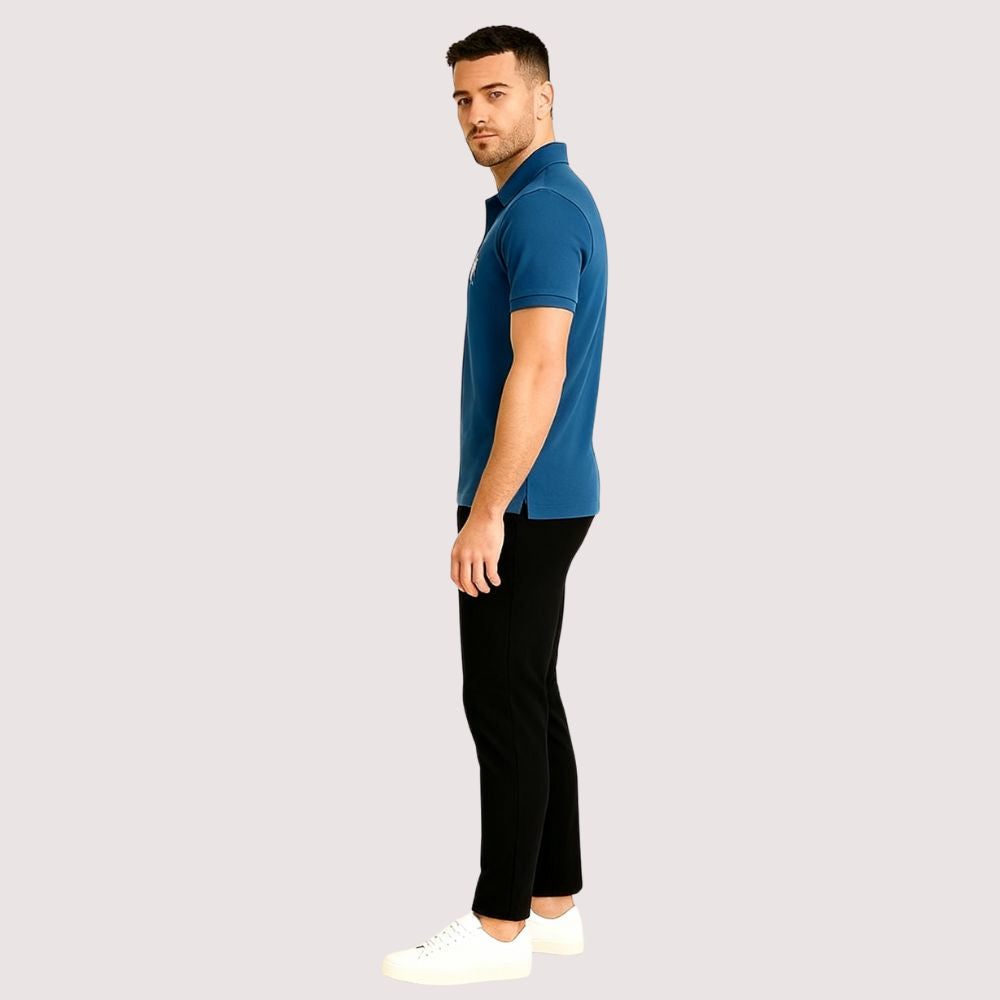 Model wearing the Kouvr Fashion Men's Slim Fit Piqué Polo in Azure Blue with black pants.