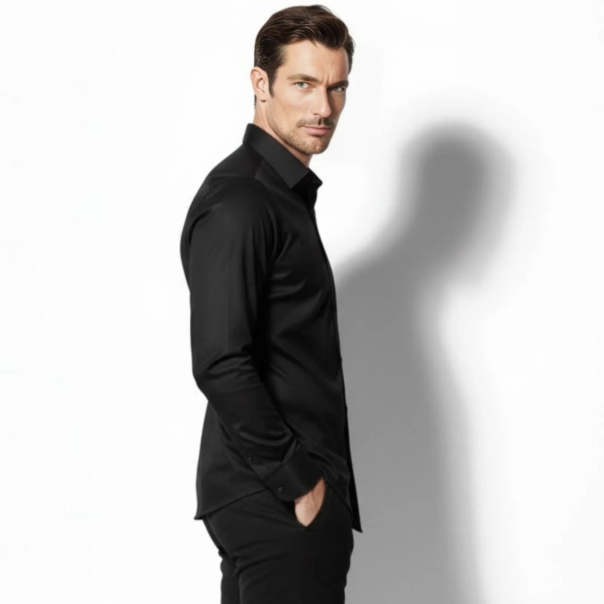 Side profile of a man wearing the Kouvr Fashion Briar tailored black long-sleeve shirt, showing its slim fit and drape.
