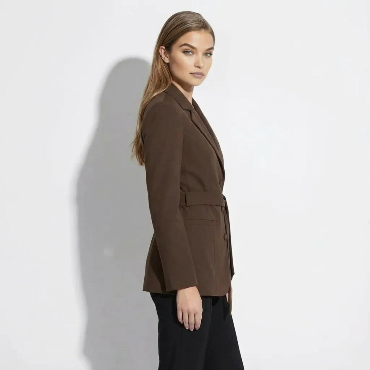 Side profile of a woman in a structured brown blazer with a self-tie belt from Kouvr Fashion. 