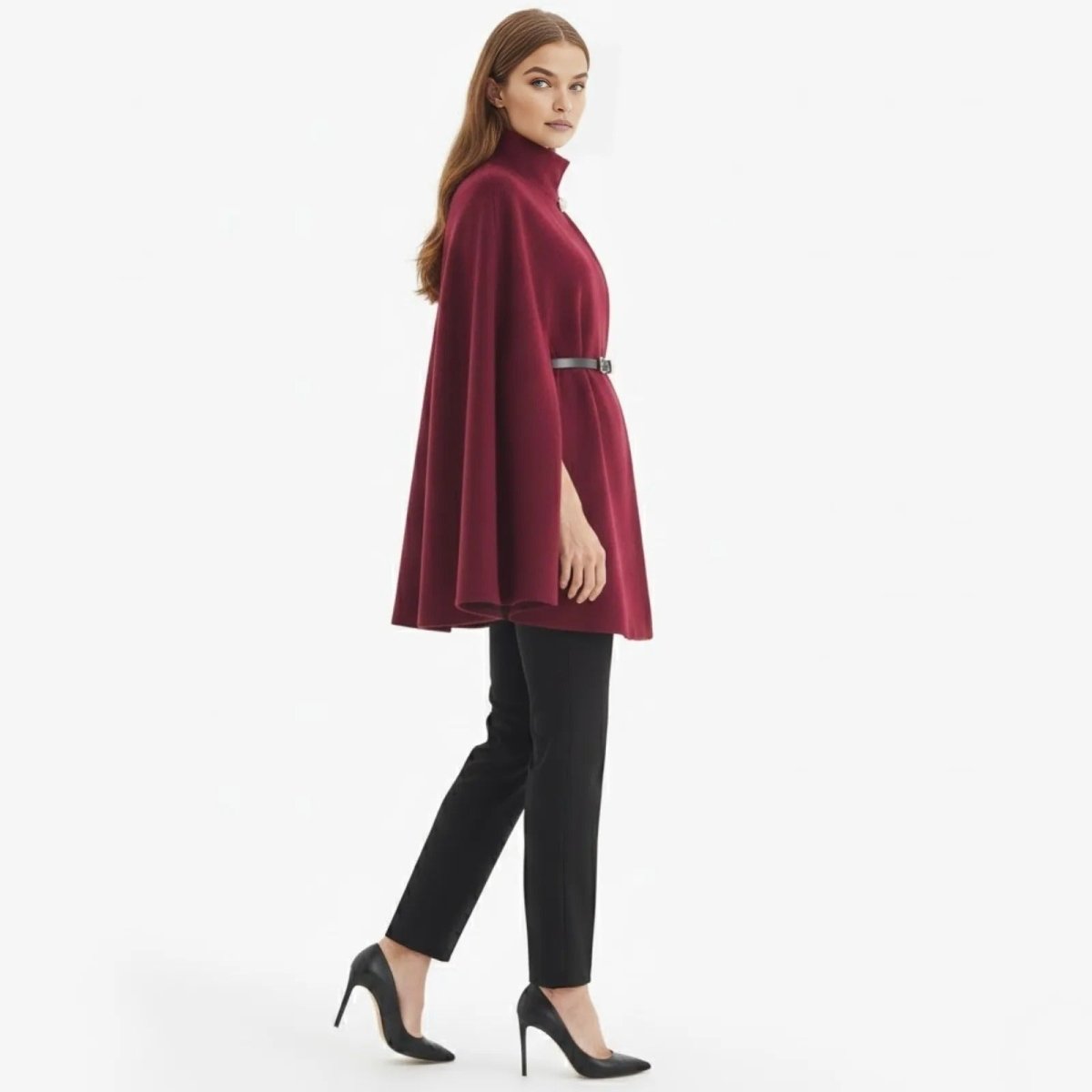 Side profile of a model walking in the Kouvr Fashion elegant red wool-blend cape, showing its drape and length with black trousers. 