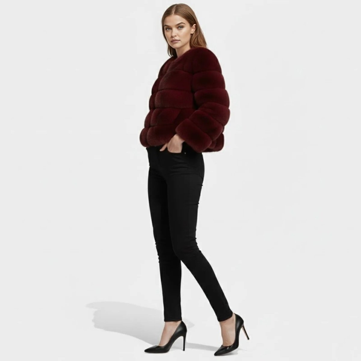 Side view of a woman wearing a short, panelled burgundy faux fur coat, showcasing its silhouette. 