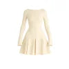 Model wearing the Kouvr Fashion Chessie long sleeve mini dress in white with button cuff details