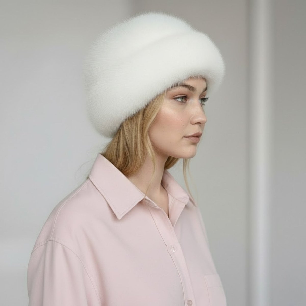 Woman wearing a white shirt and a white fur hat against a plain background