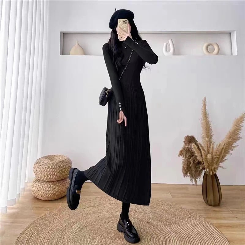 Full-length view of a woman in the black Dannah pleated knit dress by Kouvr Fashion, paired with a black beret and chunky loafers for a chic look.
