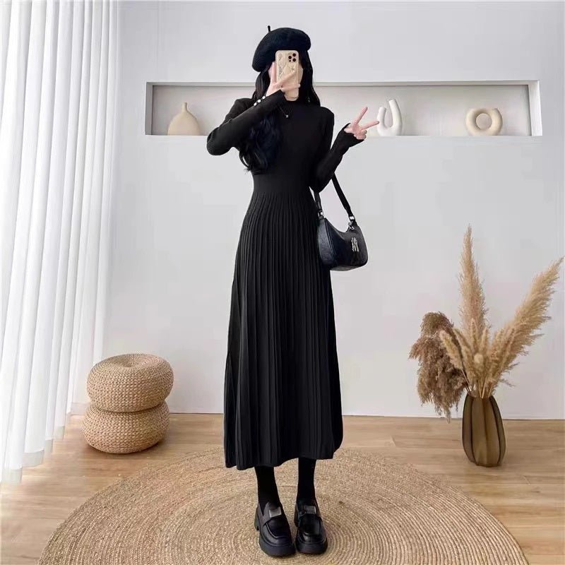 Full-length view of a woman in the black Dannah pleated knit dress by Kouvr Fashion, paired with a black beret and chunky loafers for a chic look.