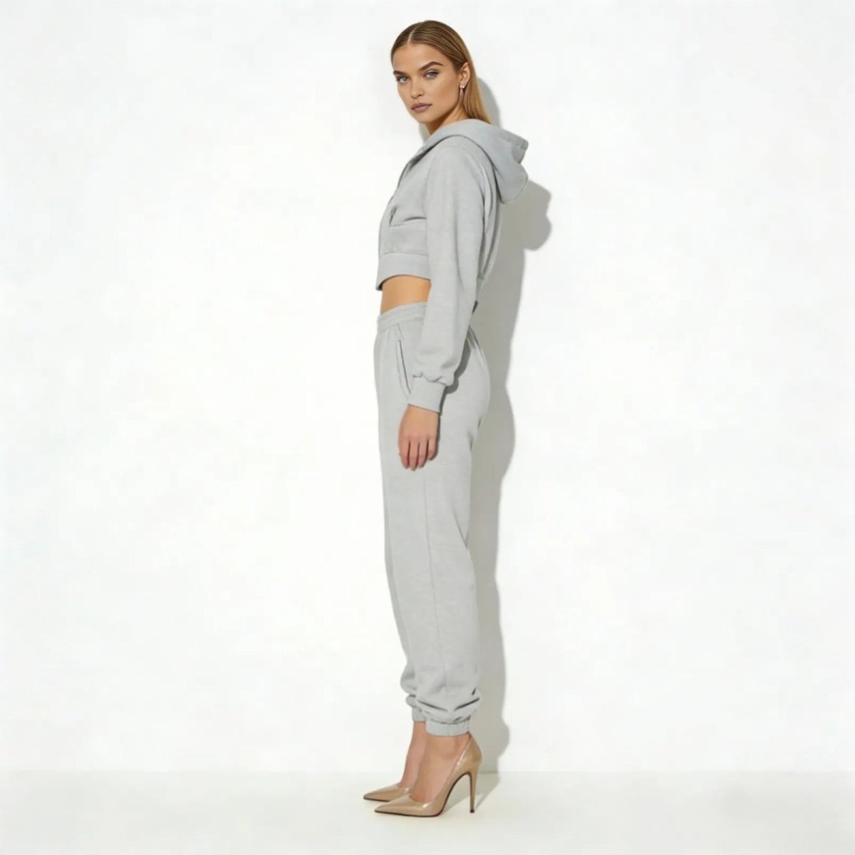 Side profile of a model in the Kouvr Fashion Ellaine heather grey loungewear set, showcasing the cropped hoodie silhouette and jogger fit.