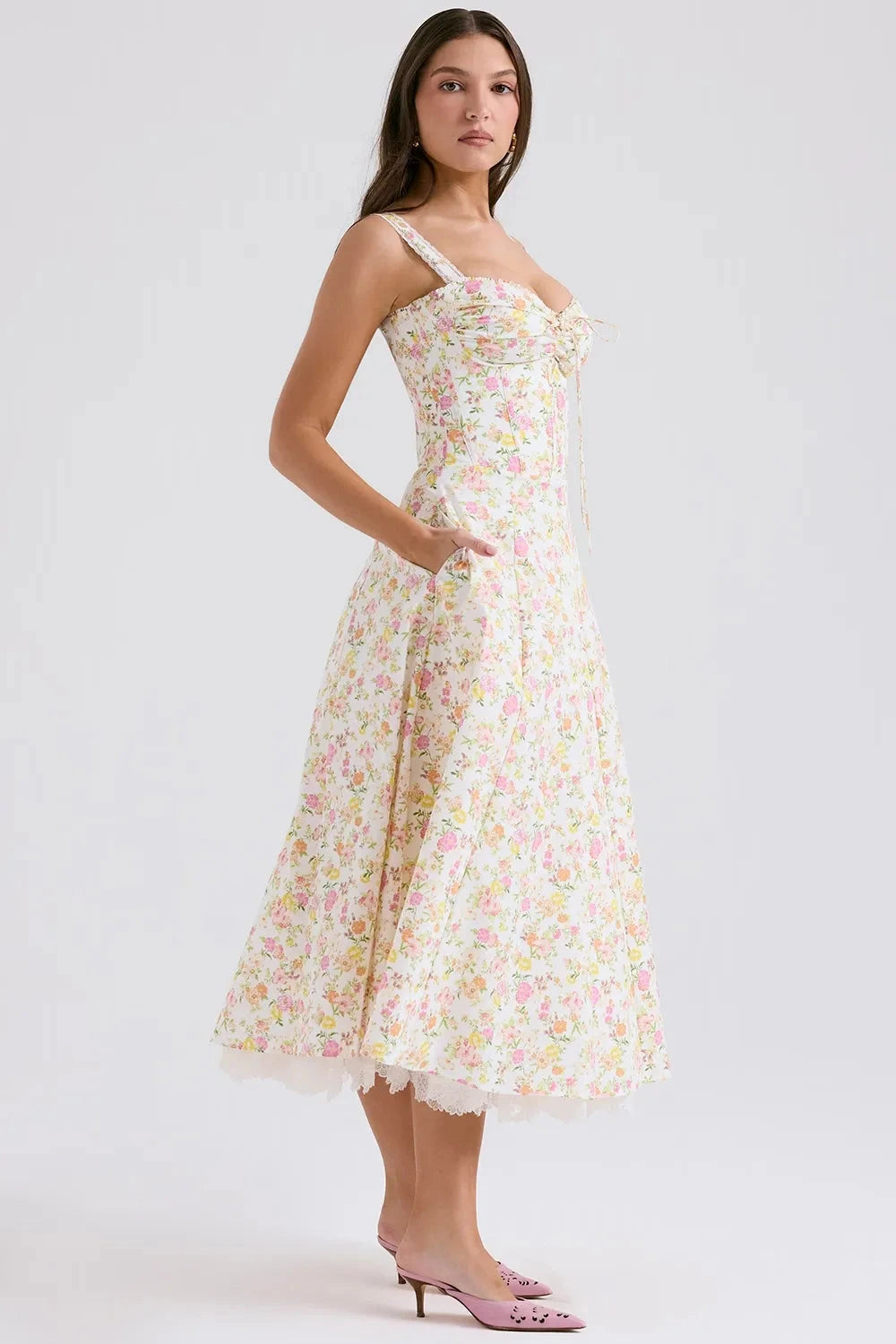 Model wearing Kouvr Fashion Eloise floral corset midi dress in white with pink and yellow flowers, showing the lace-up bustier and A-line skirt