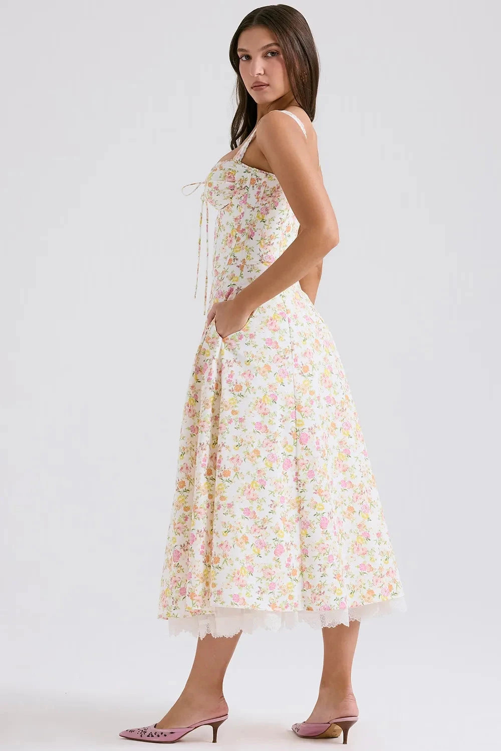 Model wearing Kouvr Fashion Eloise floral corset midi dress in white with pink and yellow flowers, showing the lace-up bustier and A-line skirt