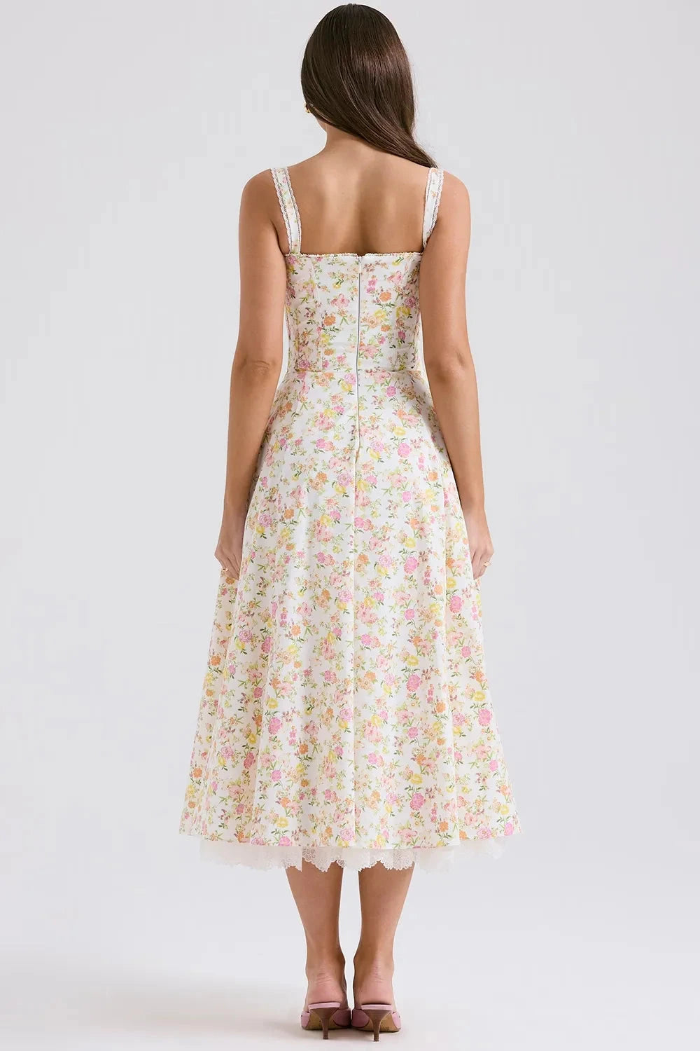 Model wearing Kouvr Fashion Eloise floral corset midi dress in white with pink and yellow flowers, showing the lace-up bustier and A-line skirt