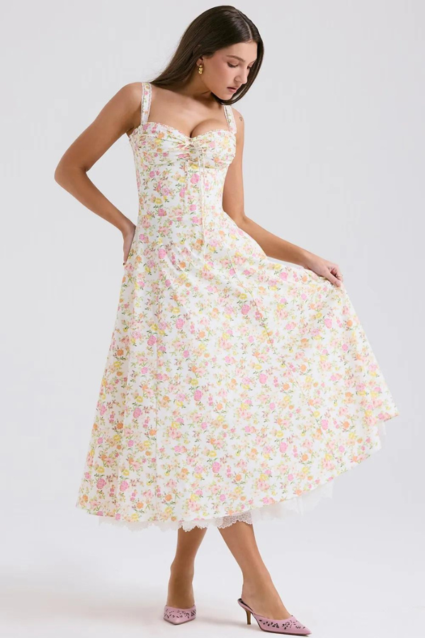 Model wearing Kouvr Fashion Eloise floral corset midi dress in white with pink and yellow flowers, showing the lace-up bustier and A-line skirt