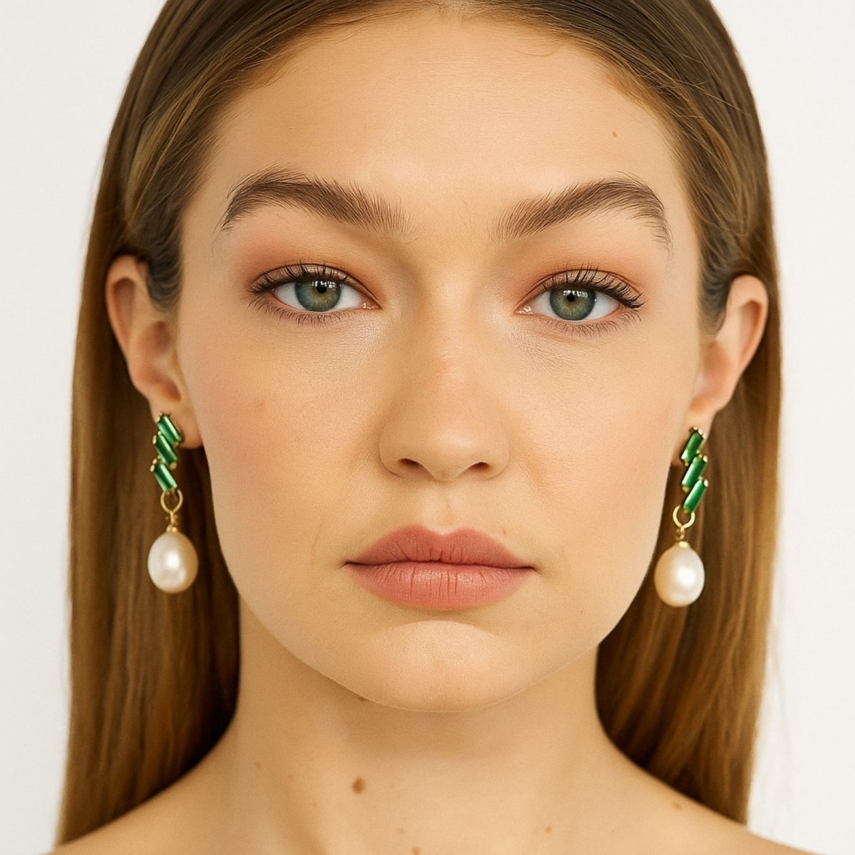 Close-up of a woman wearing Kouvr green and gold earrings with pearl-like beads.