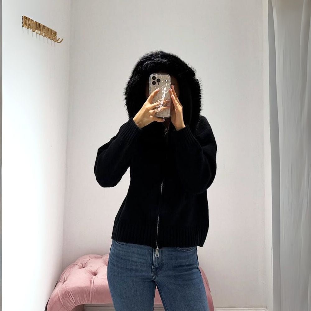 Person wearing a black kouvr hoodie and blue jeans taking a mirror selfie.