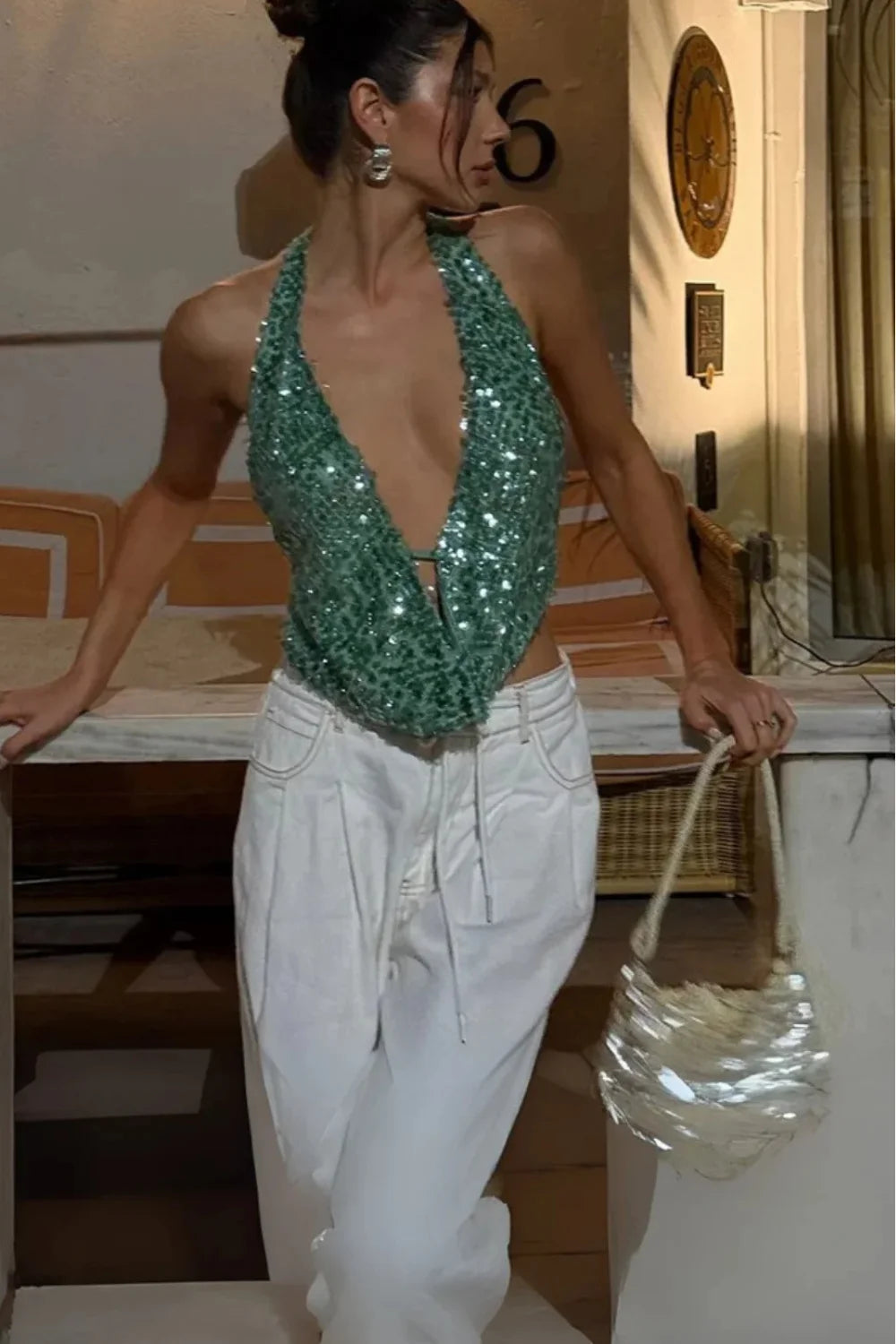 Model wearing Kouvr Fashion's backless green sequin halter top with wide-leg white pants